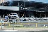 This photograph shows a view of burnt cars and a burnt Renault car shop amid protests in New Caledonia.