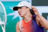 Tennis player Iga Swiatek pulls an upset face as she throws her hands and racquet up after a rally at the French Open.