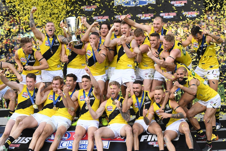 The Richmond players celebrate on the stage with the premiership cup as yellow and black confetti flies.