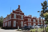 A wide shot of the brick and tile Perth Modern School in Subiaco with cars parked in front.