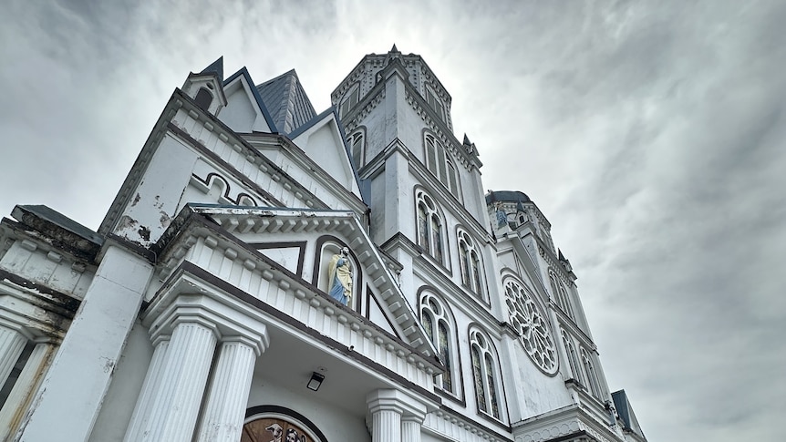 The white facade of Immaculate Conception Cathedral in Samoa, under a grey sky.