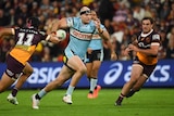 NRL player Thomas Hazelton of the Sharks, with tape around his head, makes a run between defenders