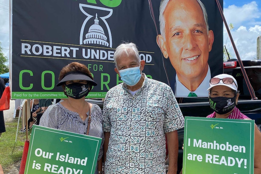 Guam politician Robert Underwood campaigns on the island. He is standing in front of his billboard alongside supporters