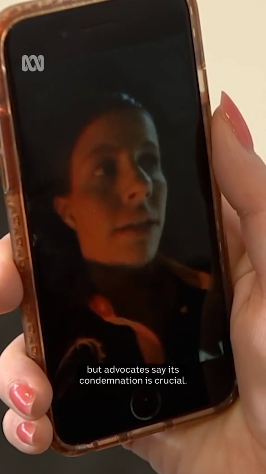 A white person's hand holds a smart phone showing a close-up of a woman's face at night