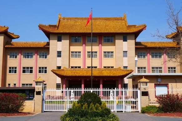 A large building with a white gate and a red flag flying outside