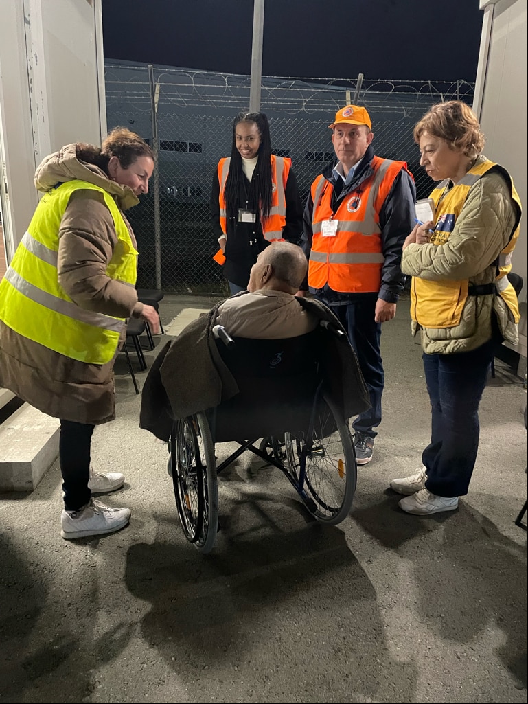 DFAT staff help a man in a wheelchair.