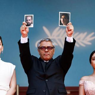 Le réalisateur iranien Mohammad Rasoulof, entouré de deux de ses actrices, mais brandissant la photo de deux comédiens absents.