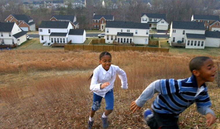 Amani Moore, 8, chases her brother Ronald Moore, Jr., 7, behind their home in Dumfries, Va., in this March photo. White adults were more likely than black and Hispanic adults to have college degrees and to own their own homes, according to data released Tuesday by the Census Bureau.