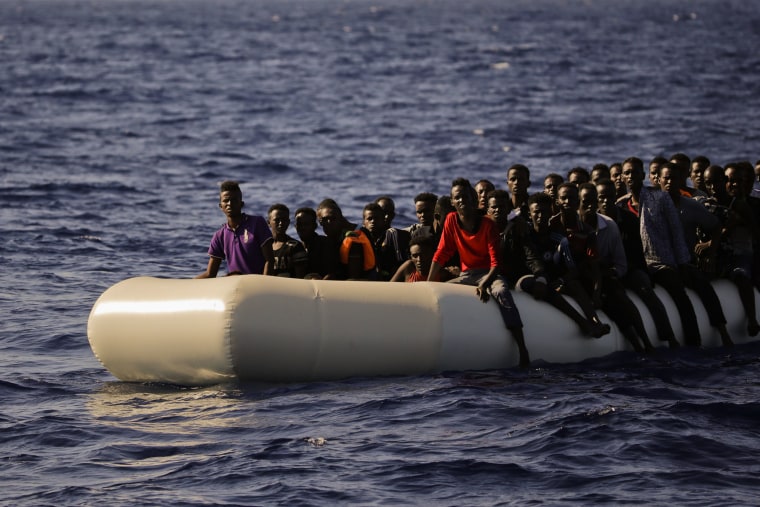 Image: Migrants fleeing Libya on board of a dinghy wait to be rescued