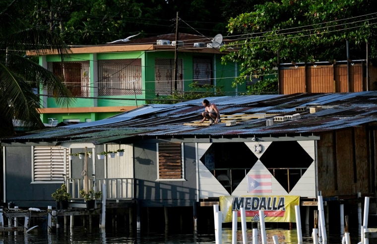 Image: A man fixes a tin roof on a house in Cabo Rojo as Tropical Storm Dorian approaches Puerto Rico on Aug. 27, 2019.