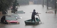 A man rows a boat on a flooded street in Brazil