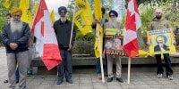 Sikh community members hold Canadian flags and signs