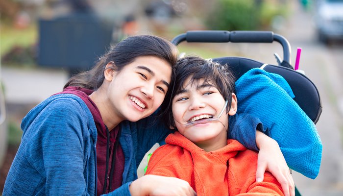 Happy young boy in a wheelchair posing with his sister