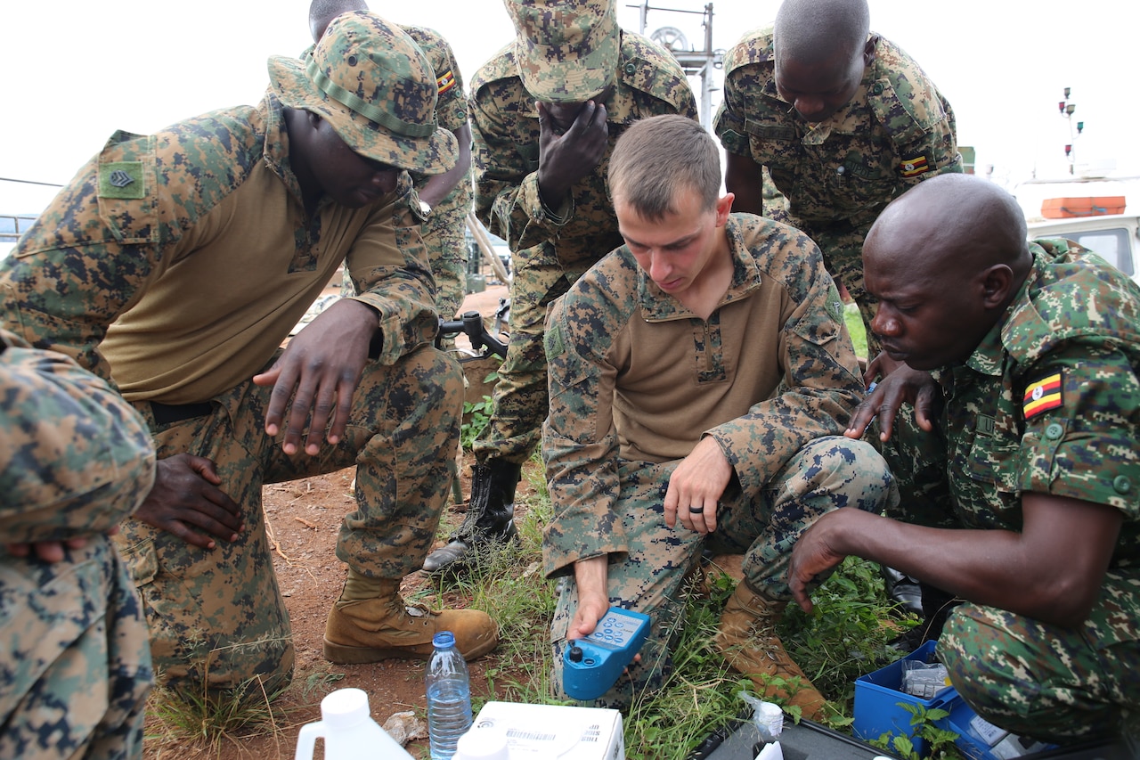 A group of Marines and Ugandan soldiers perform a water test