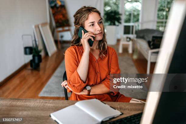 giovane donna che parla al telefono intelligente nell'ufficio di casa - parlare foto e immagini stock