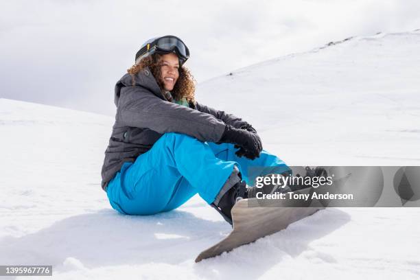young woman on snowboard sitting on snow covered slope - winter sport stock pictures, royalty-free photos & images