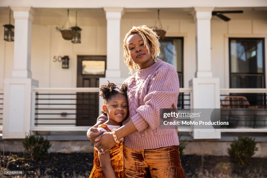 Portrait of mother and daughter in front of home