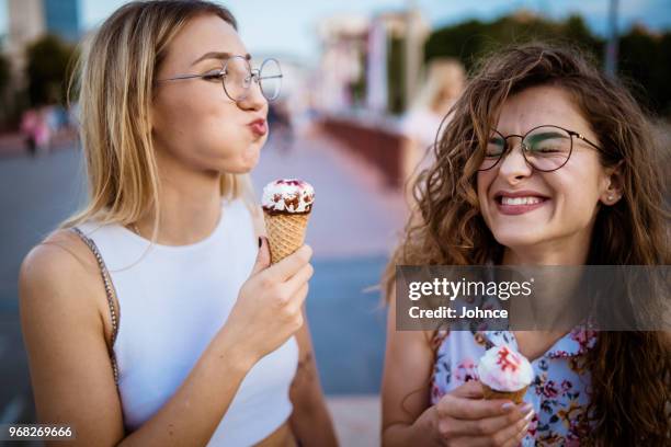 belle donne che mangiano gelato a piedi - gelato foto e immagini stock