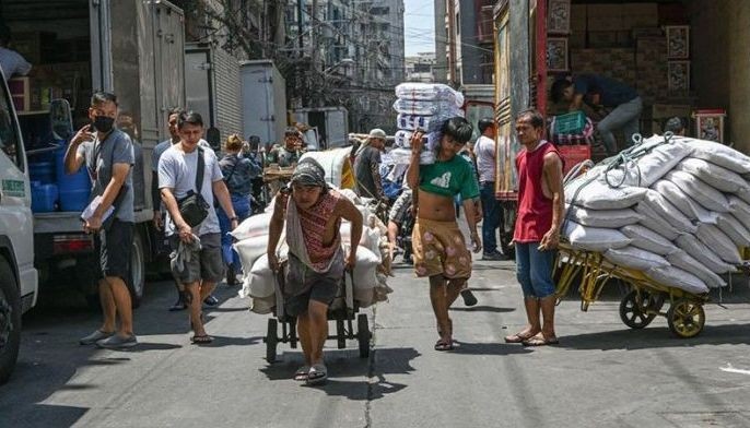Men pull a trolley of agricultural products along a street in Manila on May 9, 2024.