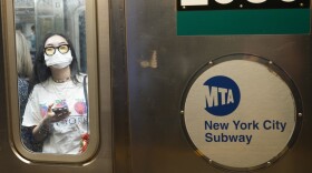 Commuters, one wearing a mask, ride the subway in New York on June 14, 2024. 