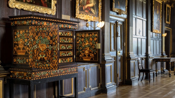 Marquetry Cabinet in the Long Gallery at Ham House and Garden, Surrey with paintings on the wall in the background