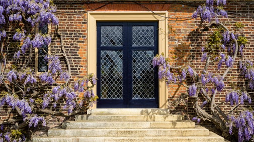 A symmetrical view of the door into the Orangery, with lilac wisteria adorning the wall on either side.