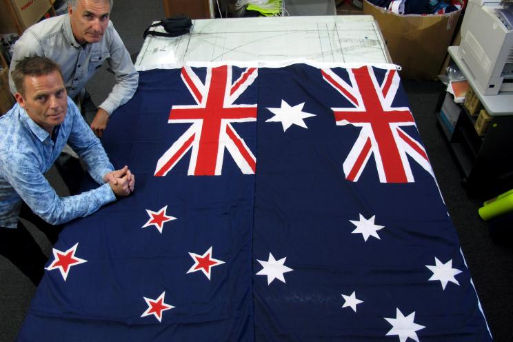 Two managers at a flag manufacturing company stand next to an Australian (right) and New Zealand flag. Many consider the current flag to be too similar to Australia’s.