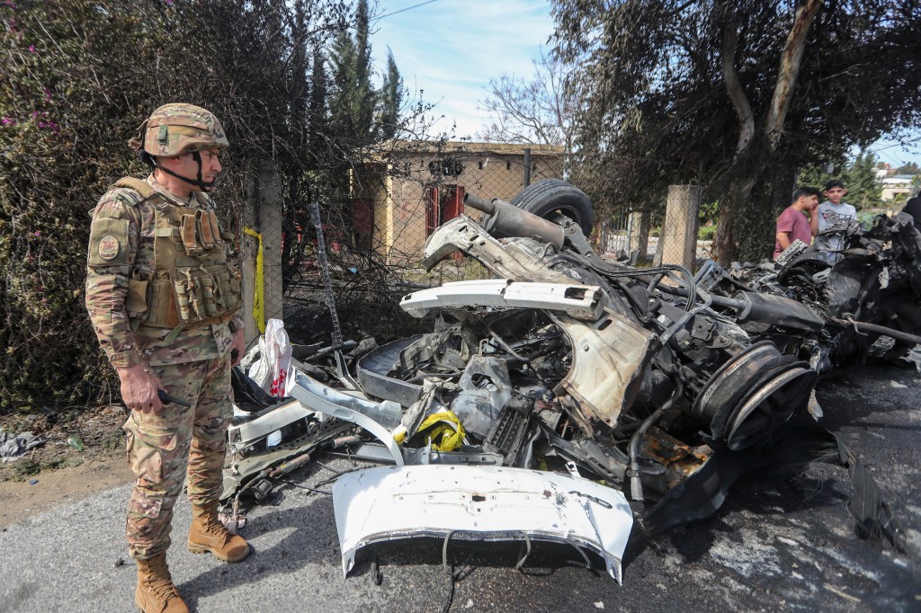A Lebanese army officer stands next to a destroyed car in the southern outskirts of Tyre