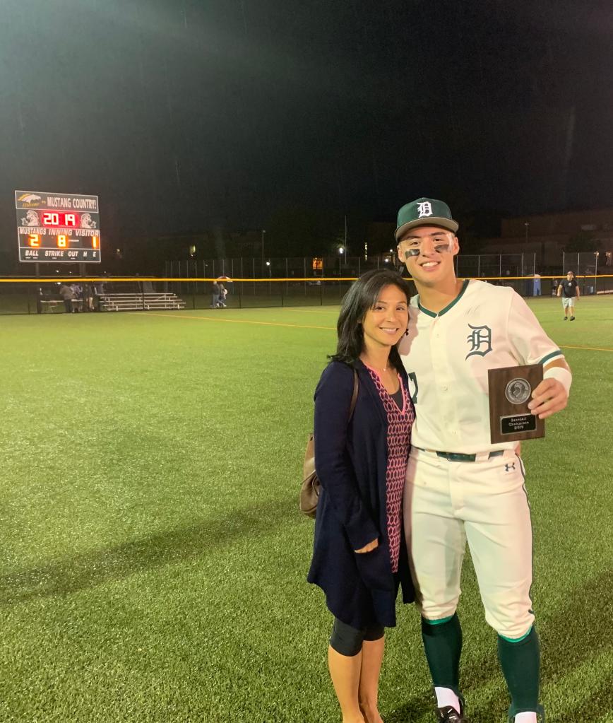 Isabelle Volpe and her son posing on a field while he holds an award