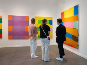 Art fair goers look at a trio of colorblock paintings
