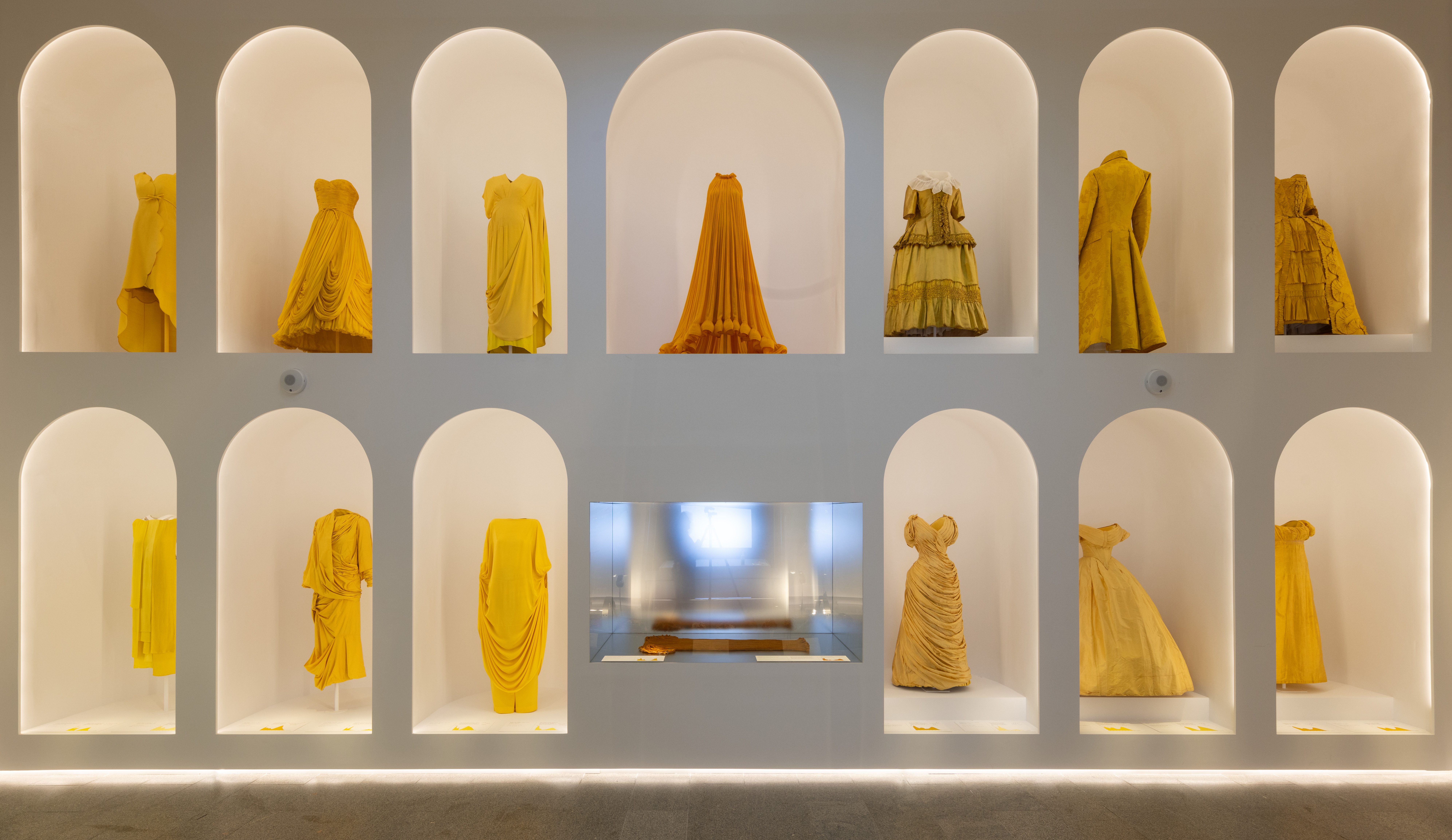 Gowns in shades of yellow and orange displayed in alcoves