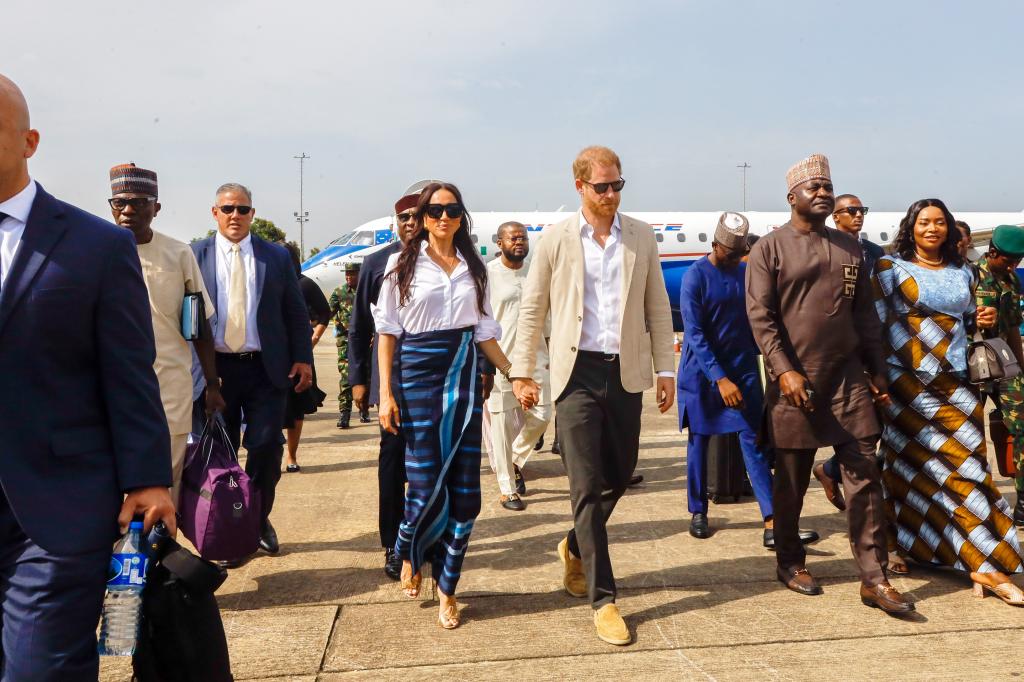 Meghan Markle, in a blue skirt, and Prince Harry arrive at Lagos airport.