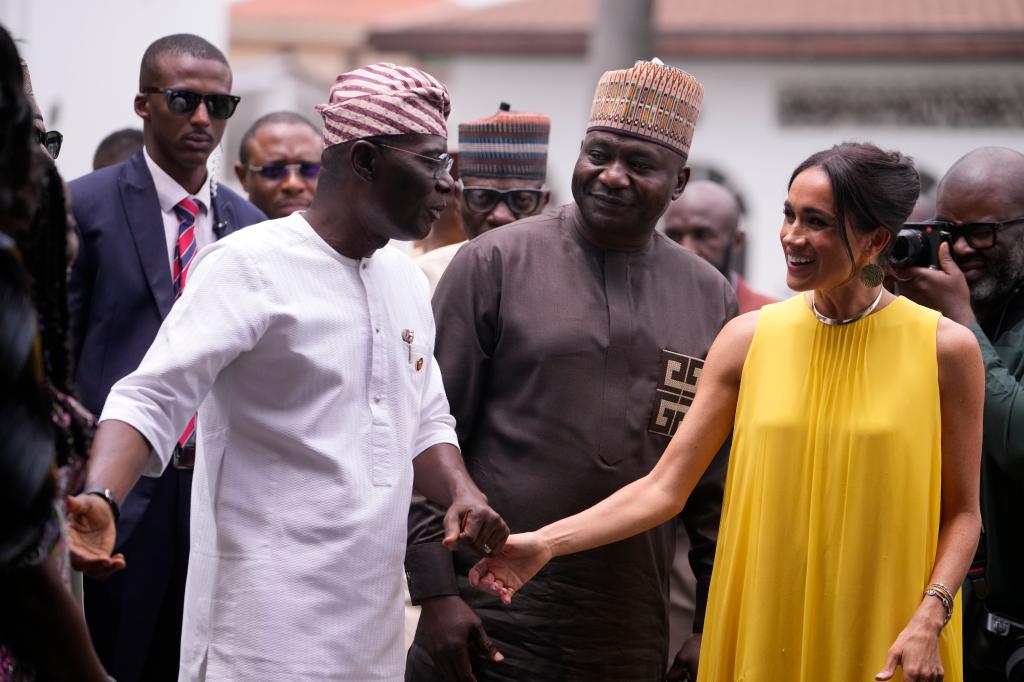 Meghan Markle, in a yellow gown, is welcomed by BabaJide Sanwo-Olu, Lagos state governor, left, at the government house in Lagos Nigeria.