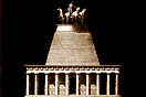 
[image ALT: A ten-columned temple surmounted by a pyramid capped with a quadriga. It is a 19th‑century idea of the Mausoleum of Halicarnassus.]
			