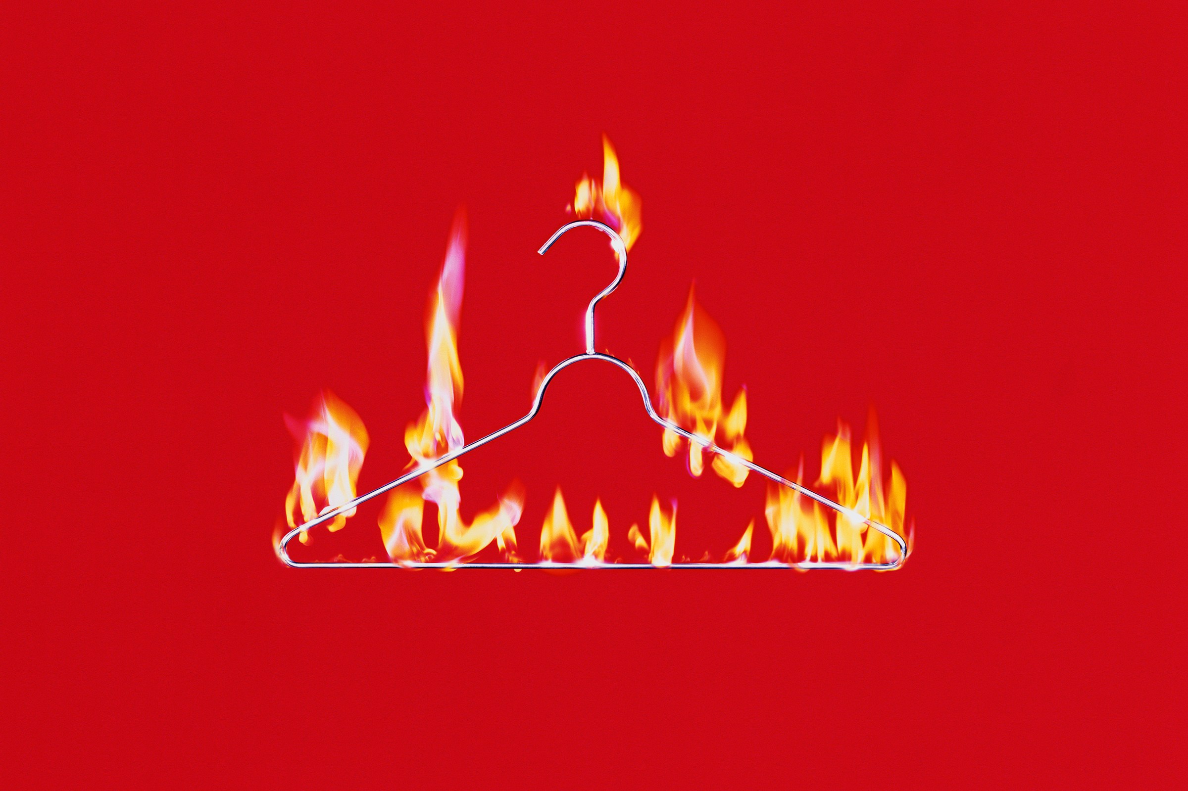 burning clothes hanger on red background