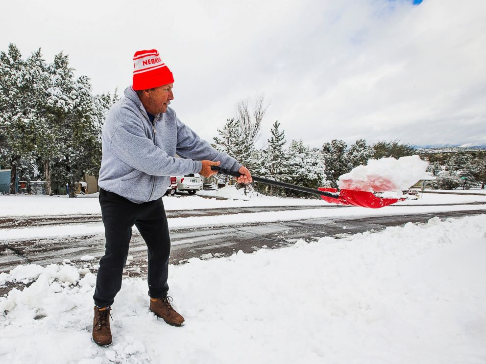 PHOTO: David Rutter shovels on his driveway after snow fell covering the area with a few inches in Payson, Ariz., Dec. 14, 2015. 