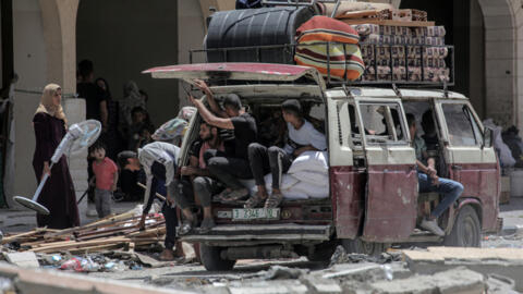 Palestinians who fled Rafah in the southern Gaza Strip unload their belongings from the back of a truck upon their arrival to take shelter in Khan Younis on May 12, 2024.