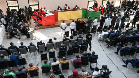 Les onze accusés se tenant debout alors que l'audience commence à l'intérieur du nouveau palais de justice de Conakry le 28 septembre 2022, lors de l'ouverture du procès pour le massacre de 156 personnes en septembre 2009.