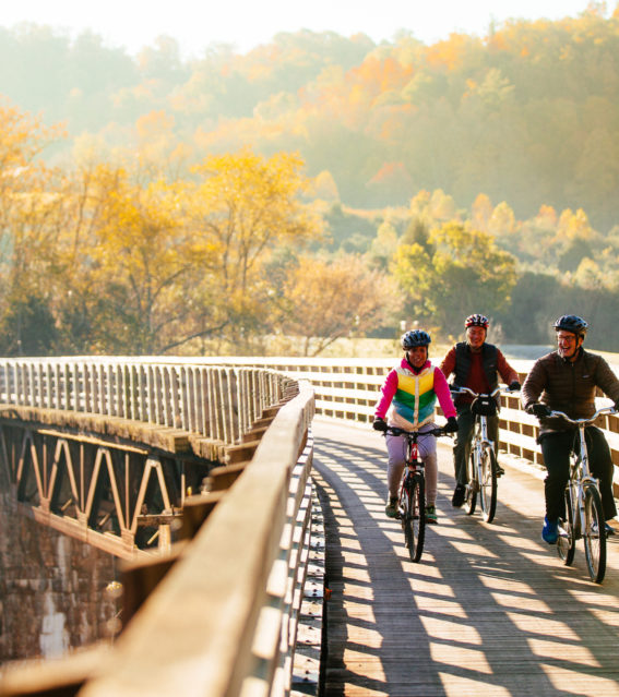 Virginia Creeper Trail bike riders on trestle in fall - horizontal - credit Sam Dean