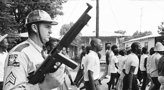 A heavily armed white trooper menacing a protest march through Bogalusa, Louisiana, in 1965.