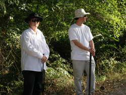 Ellen Schattschneider, Two reenactors playing Klansmen wait near the Moore's Ford Bridge, Walton County, Georgia, July 25, 2009.