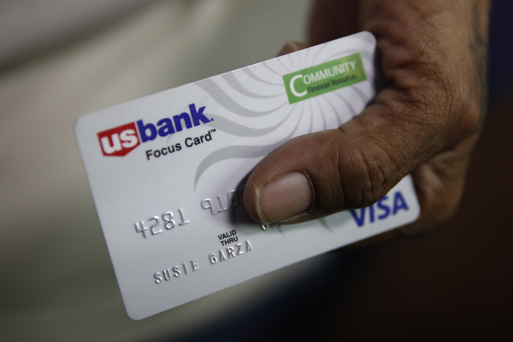A woman displays a debit card.