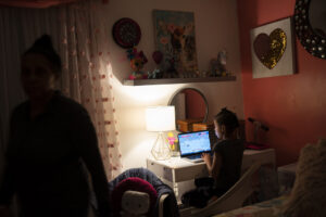 A girl at a computer in her room.