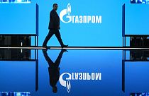 A man walks at an exhibition at the St. Petersburg International Gas Forum in St. Petersburg, Russia, Wednesday, Sept. 14, 2022, with a logo of Russian gas monopoly Gazprom.
