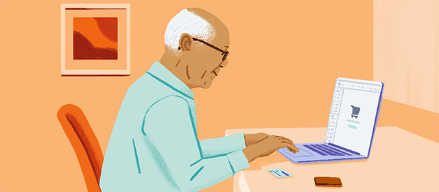 An elderly man sitting at a desk and using a credit card to shop on his laptop.