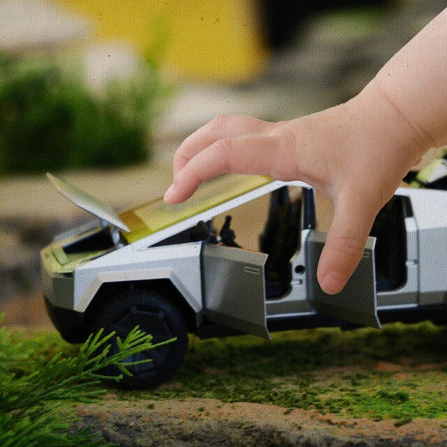 A close-up photograph of a child’s hand and a toy model of a sharply angular vehicle. 