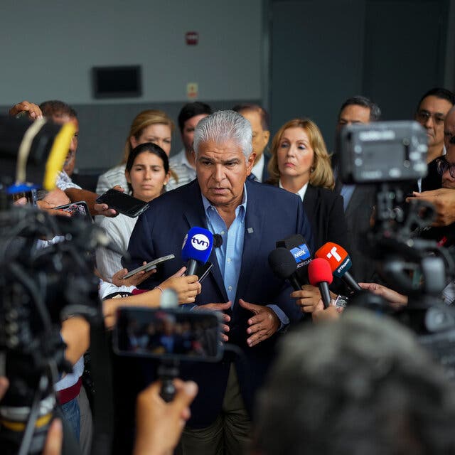 José Raúl Mulino speaks to a scrum of people holding microphones and cameras.