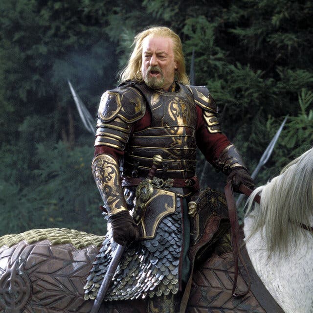 A bearded man in armor sits atop a white horse and appears to be speaking to somebody out of the picture,