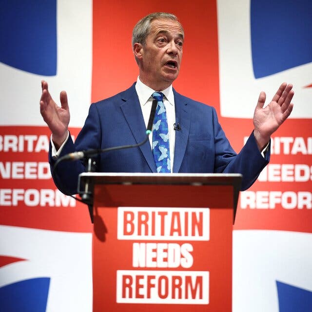 Nigel Farage standing at a podium with a large Union Jack in the background.
